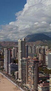 Stunning aerial view of mediterranean city benidorm in spain with skyscraper buildings mountains and clouds.