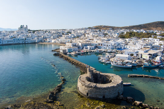 Naoussa, Paros, Greece - 21 September 2026: Aerial view of the historic Venetian castle ruins in the harbour of Naoussa with white buildings and fishing boats in turquoise water.