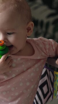 Close up portrait of cute 6-7 month old baby biting green silicone teether toy. Teething relief, itchy gums, first teeth symptoms, and infant care