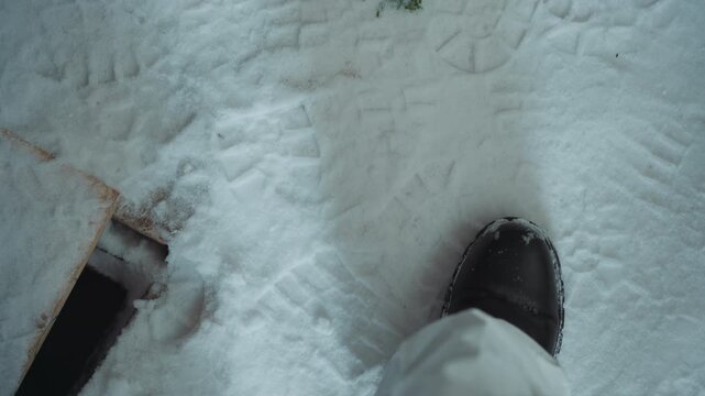 Boots in snow survivor inspects patch lone figure in worn protective clothing examines greenish stains and scuffed footprints by porch of abandoned house, radio faintly crackling, frost patterns