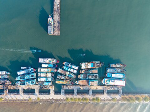 Aerial view of fishing boats moored at a concrete pier in the harbor of Probolinggo, East Java, Indonesia.