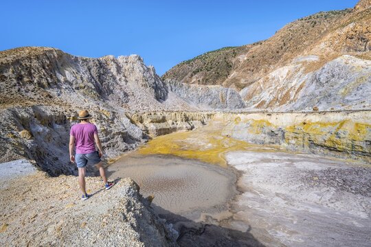 Young tourist at a crater, volcano caldera with pumice fields, yellow coloured sulphur stones, Alexandros crater, Nisyros, Dodecanese, Greece