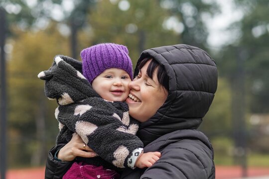 Mother hugging baby cheek to cheek outdoors
