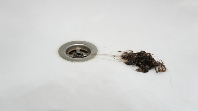 hair clump, clogged bathtub drain metal drain, white tub, loose hair strands, dark hair clump, wet hair, drain cleaning, bathroom plumbing