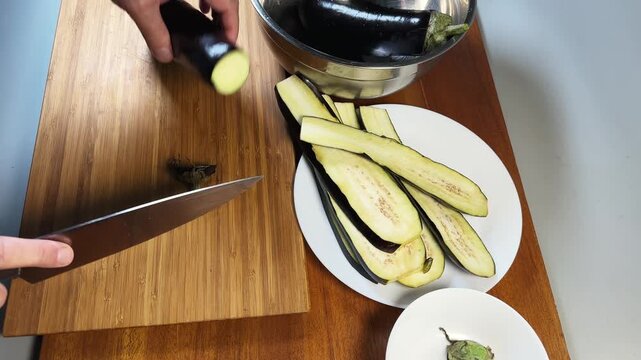 Cutting eggplant lengthwise into two halves on a cutting board