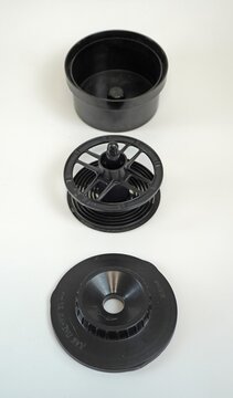 Disassembled film developing tank parts arranged vertically. Tank body, reel, and lid separated on white background for photography equipment display.