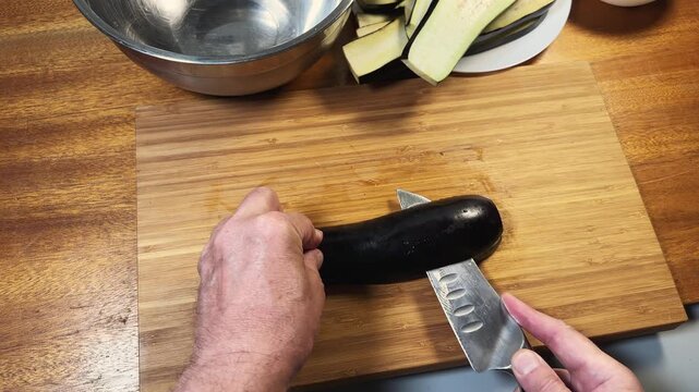 Slicing eggplant lengthwise into long strips on a cutting board