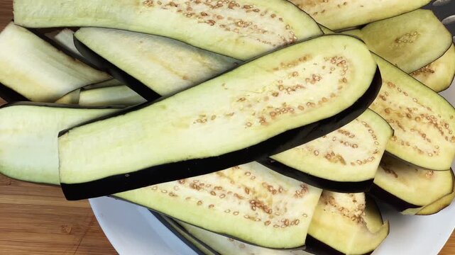 Long slices of purple eggplants cut lengthwise on a plate