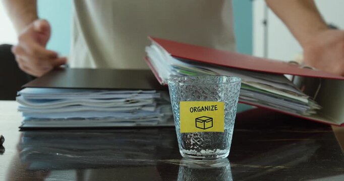 Person throws folders onto a table near an Organize reminder, representing clutter and work overload.
