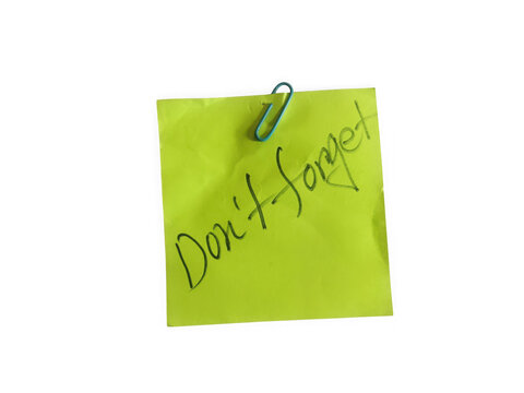 Bright green sticky note with a blue paper clip and the handwritten text message dont forget isolated on transparent background