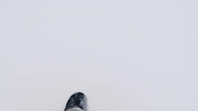 Man walking in deep snow outdoors, top down view on legs and boots in winter landscape.