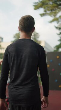 Man walking on an outdoor sports gym. Young athlete on an outdoor training ground. Walking sporty man.