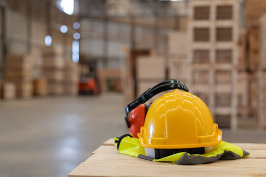 A yellow hard hat  on a wooden surface in a warehouse filled with stacked pallets