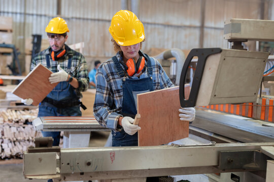 Worker measures wood in a warehouse during the day while wearing safety gear
