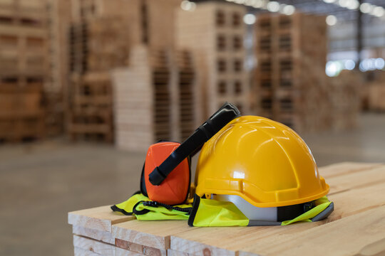 A yellow hard hat  on a wooden surface in a warehouse filled with stacked pallets