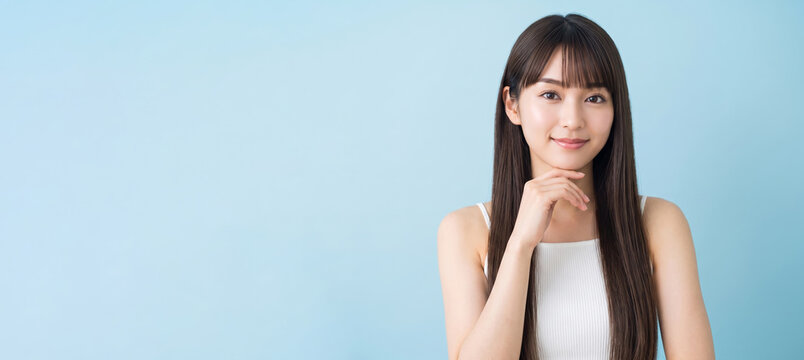 あごに手を当て微笑むロングヘアの女性