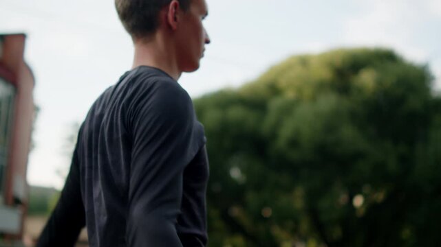 Athlete performing a dynamic upper body stretching routine before a workout at an outdoor gym. Man warming up shoulders beforea calisthenics training on an outside training ground.
