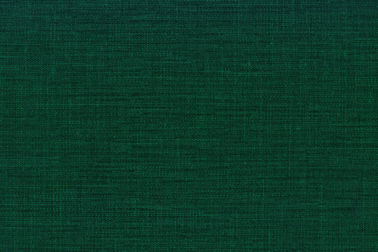 Dark emerald green textile texture with visible woven grain, irregular variations and subtle intersecting lines across the surface.