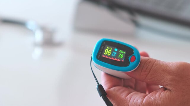 Doctor using a pulse oximeter on a patient's finger to measure oxygen saturation and pulse rate