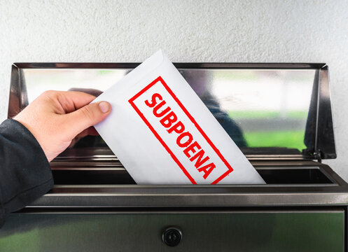 Hand dropping a legal subpoena envelope into a mail slot