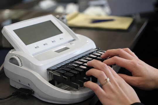 Stenographer typing on a digital stenotype machine in a courtroom