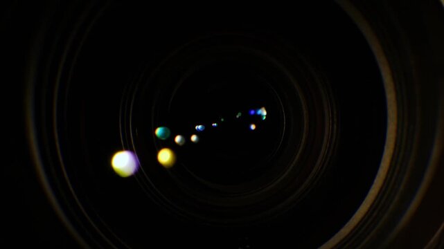 Dynamic close up of a camera lens aperture opening and closing with colorful bokeh lights.