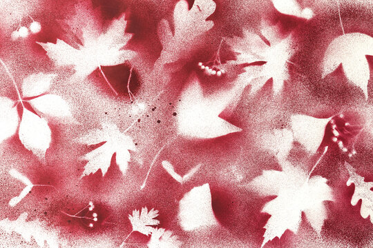 Handmade crimson red spray paint art print with white maple leaf silhouettes on textured paper. Suits a winter holiday campaign and seasonal branding.