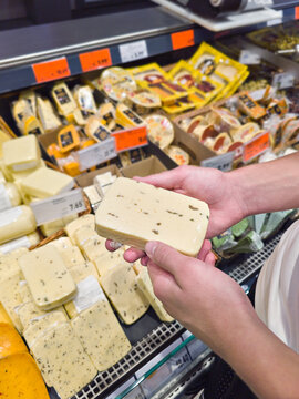 Shopper Choosing Herb Cheese at Supermarket Dairy Counter