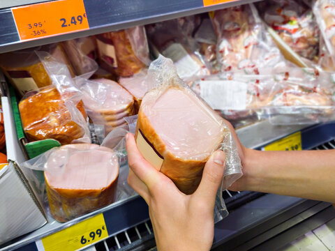 Shopper Choosing Packaged Ham at Supermarket Meat Counter