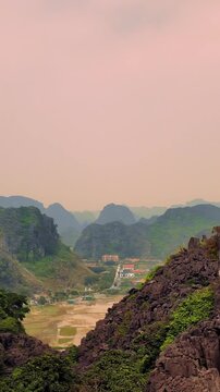 Pan Shot of Limestone Mountains, Rice Fields, and Villages in Ninh Binh During Soft Afternoon Haze