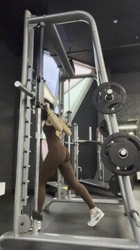young woman doing squats in Smith machine