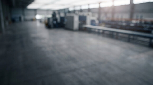 Blurred industrial factory interior background with out of focus warehouse machinery and spacious concrete floor for manufacturing concepts.