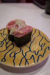 Two pieces of negitoro gunkan maki sushi, minced fatty tuna with green onion wrapped in nori, on a plate at a Japanese conveyor belt sushi restaurant © Kazuki Yamakawa