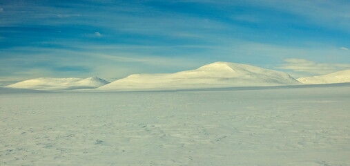 Enontekiö, Finland - 05.04.2023: Expansive snow-covered mountains and pristine arctic tundra under a bright blue clear sky in Lapland © Andrei