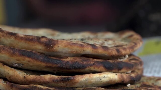 Freshly cooked flat bread or parantha being taken out from a traditional tandoor.