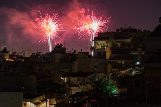 Bright pink fireworks exploding over Athens city rooftops during New Year celebration night in Greece.