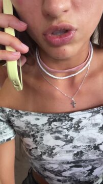 Young woman speaking on pale green smartphone held to left ear, expressive engaged face and hand gripping handset in close frontal portrait
