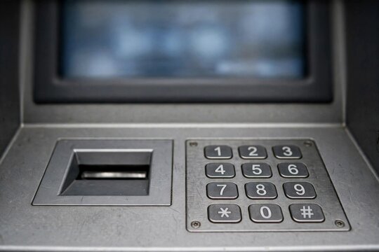 Close-up of a generic unbranded ATM cash machine with blurred screen, card slot and keypad in focus