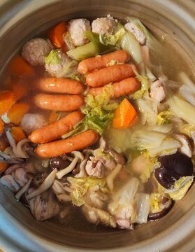 Japanese hot pot nabe cooking in clay pot with sausages meatballs and vegetables