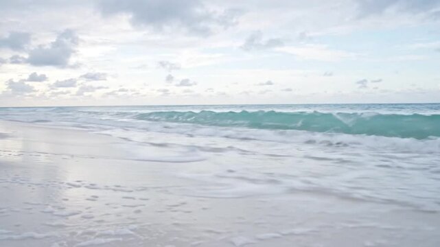 Serene Tropical Beach with Gentle Waves and Cloudy Sky, Idyllic Seaside Landscape