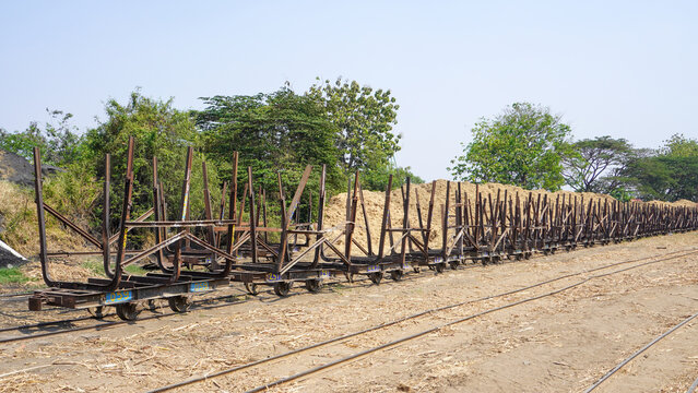 Empty traditional rusty metal sugarcane rail cars parked on narrow tracks at historical Rendeng Sugar Mill in Kudus, Central Java, Indonesia, used for transporting sugar cane during harvest.