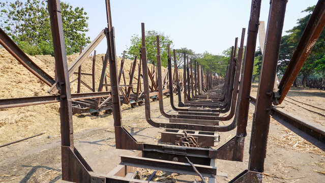 Empty traditional rusty metal sugarcane rail cars parked on narrow tracks at historical Rendeng Sugar Mill in Kudus, Central Java, Indonesia, used for transporting sugar cane during harvest.