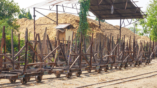 Empty traditional rusty metal sugarcane rail cars parked on narrow tracks at historical Rendeng Sugar Mill in Kudus, Central Java, Indonesia, used for transporting sugar cane during harvest.