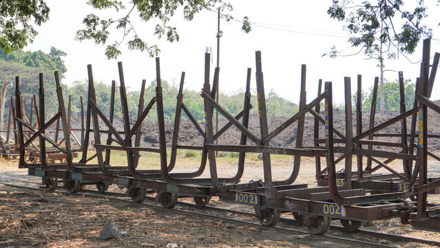 Empty traditional rusty metal sugarcane rail cars parked on narrow tracks at historical Rendeng Sugar Mill in Kudus, Central Java, Indonesia, used for transporting sugar cane during harvest.