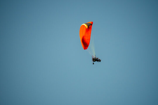 Paraglider soars high against clear blue sky