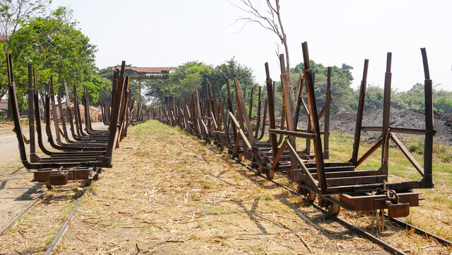 Empty traditional rusty metal sugarcane rail cars parked on narrow tracks at historical Rendeng Sugar Mill in Kudus, Central Java, Indonesia, used for transporting sugar cane during harvest.