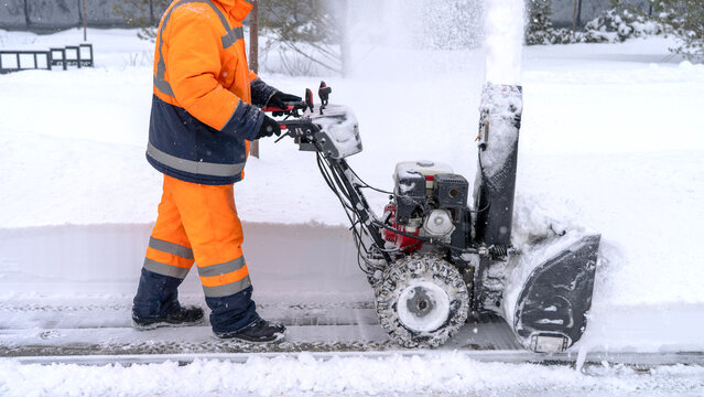 Worker clears snow with heavy-duty snowblower