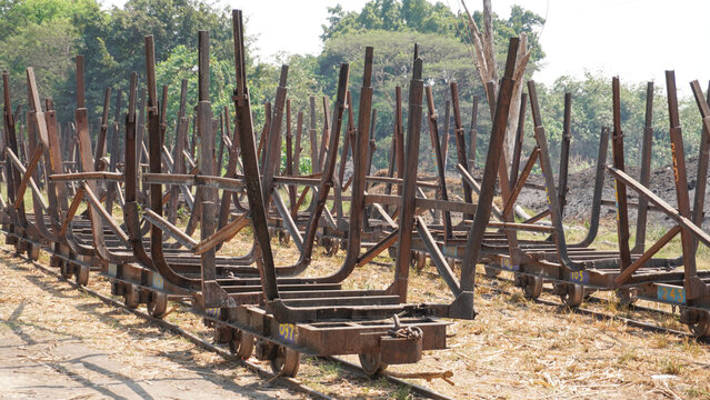 Empty traditional rusty metal sugarcane rail cars parked on narrow tracks at historical Rendeng Sugar Mill in Kudus, Central Java, Indonesia, used for transporting sugar cane during harvest.