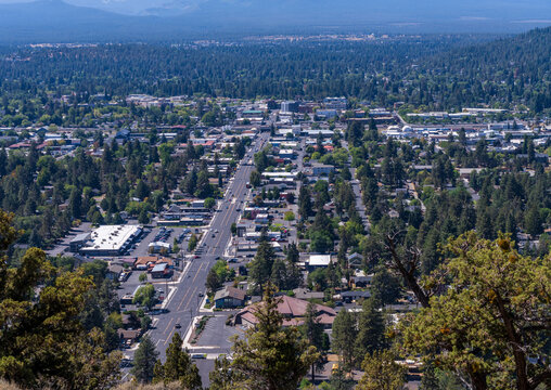 High angle view of Bend Oregons downtown area with commercial buildings and streets nestled among pine trees from Pilot Butte