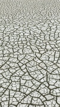 Aerial shot looking down at the cracked surface of a dry lake. Vertical video.